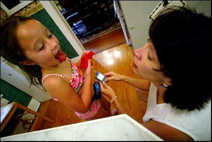 Alyssa's mother Pam adjusts her daughter's insulin pump as Alyssa sticks her 